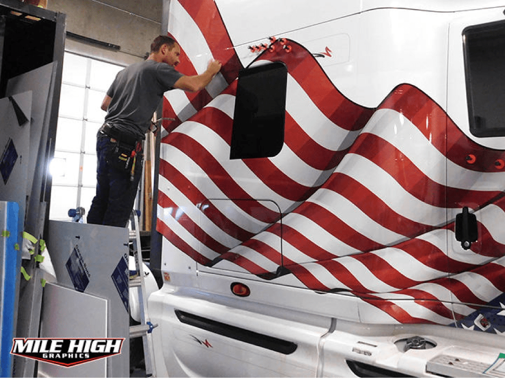 Photo of professional graphics installer applying american flag to tractor.